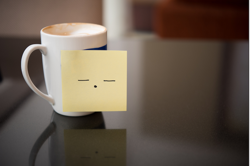 mug of hot chocolate with a sleepy face drawn on a sticky note