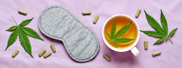 flat lay of hemp leaves, a grey sleep mask and a tea cup of tea