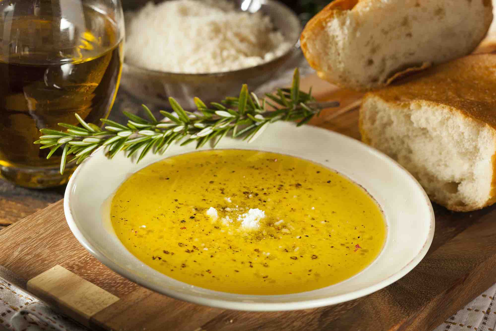 Completed bread dipping olive oil on a shallow white plate, full of spices