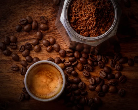 Coffee beans on top of a brown table next to cacao powder and other ingredients about to make weed coffee
